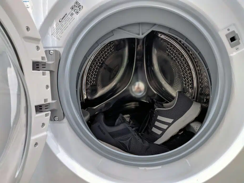 pexels-photo-4824683-4824683 Close-up of black sneakers inside a washing machine drum showcasing laundry theme.